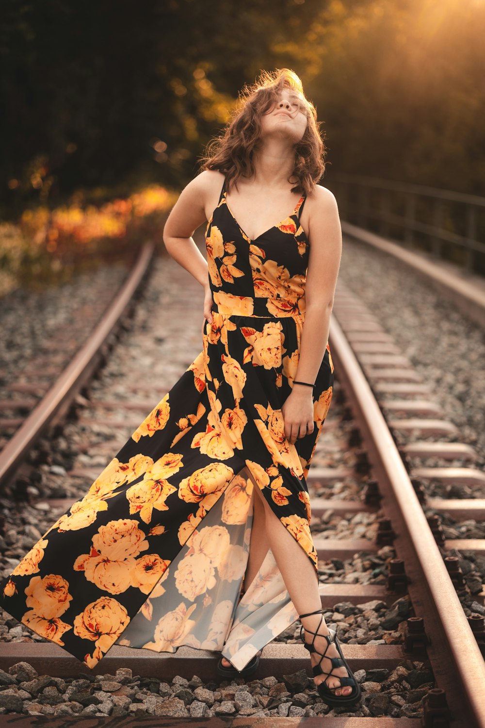 a woman in a dress standing on train tracks
