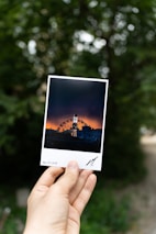 Artistic shot of a hand holding a custom photo magnet with a scenic landscape.
