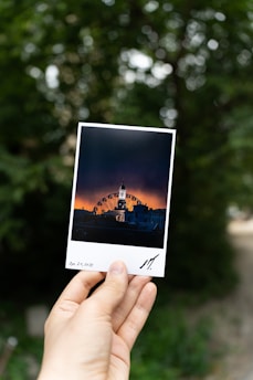 Artistic shot of a hand holding a custom photo magnet with a scenic landscape.