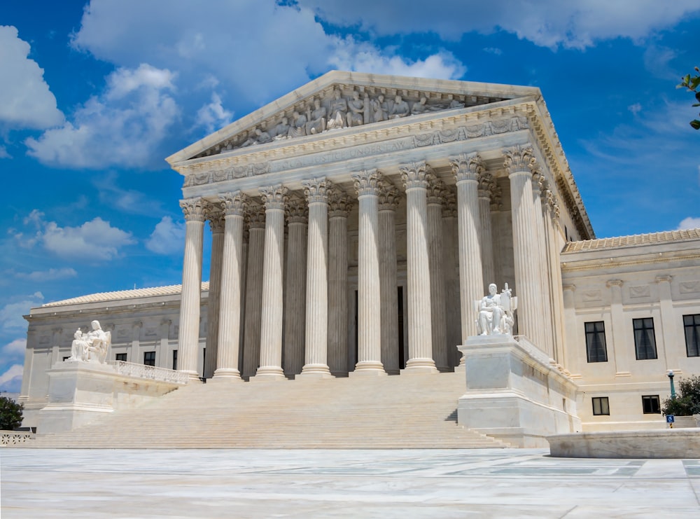 a large white building with columns with United States Supreme Court Building in the background