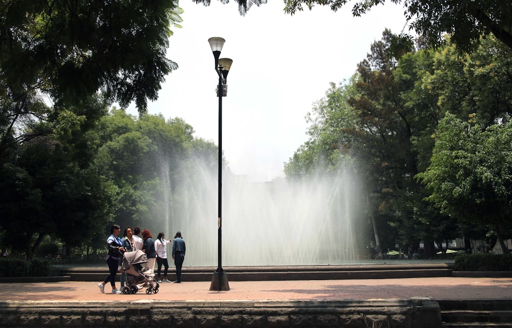 a group of people walking by a fountain