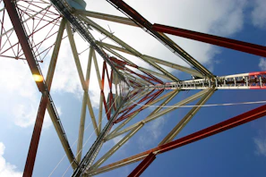 Engineer reviewing detailed structural blueprints for a telecommunications tower on a sunny day.