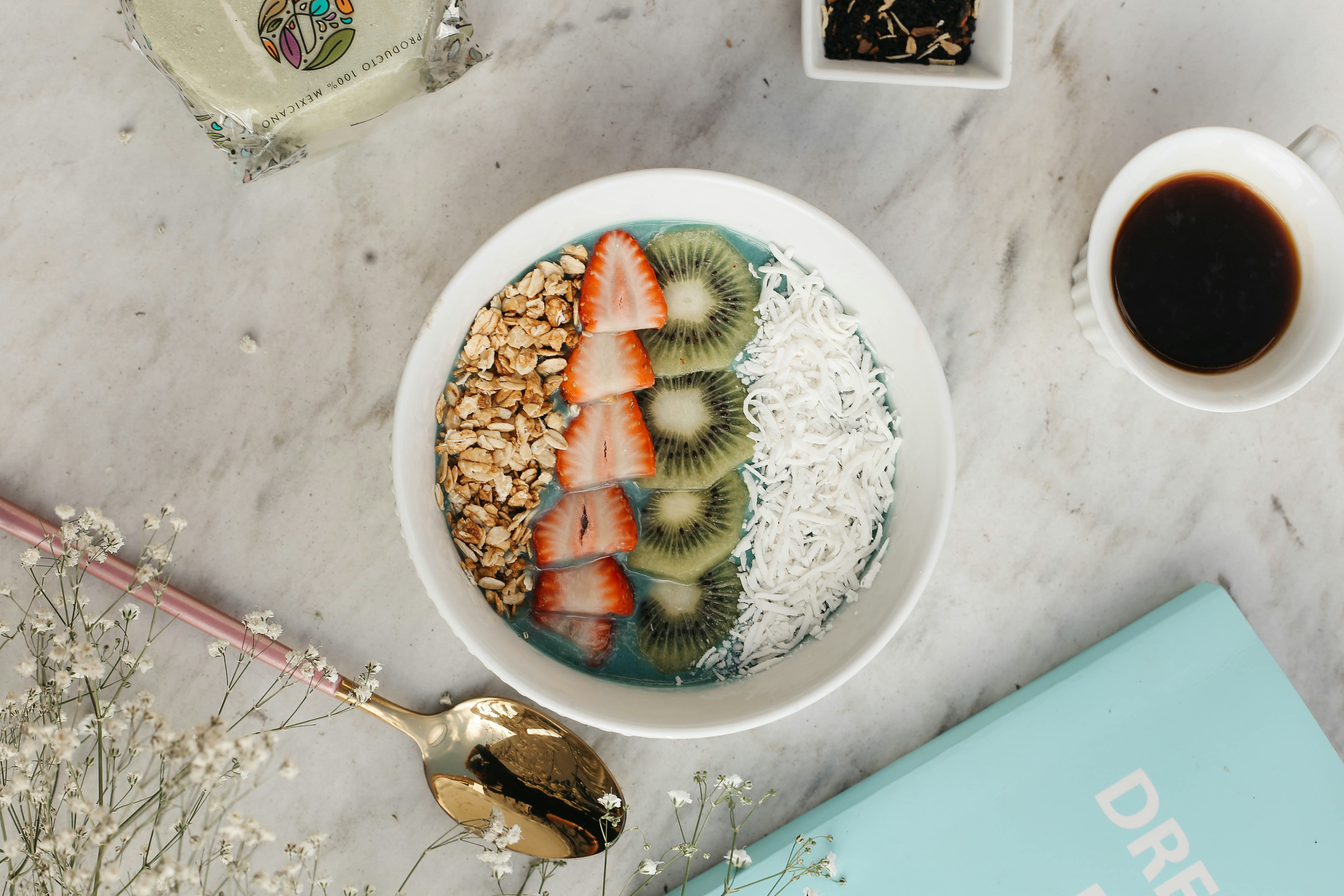 Smoothie bowl beside a coffee on marble
