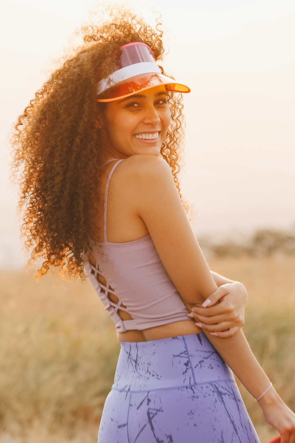 a woman in a white shirt and pink hat with her arms crossed