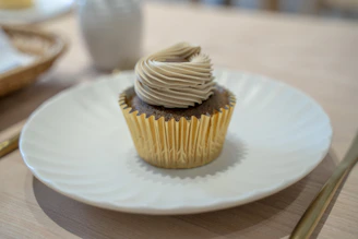 Freshly baked golden brown cupcakes with swirls of creamy vanilla frosting in a cozy kitchen setting