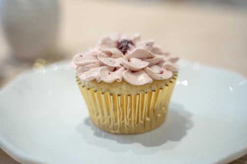 High-resolution photo of a minimalist cupcake with delicate frosting and a single berry on top.
