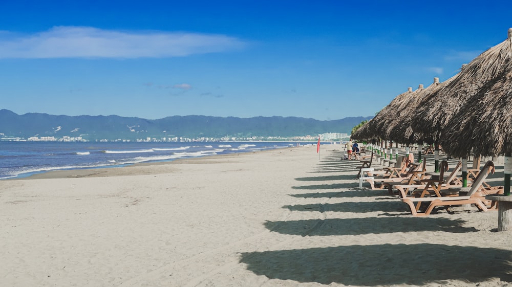 a beach with a hut and chairs