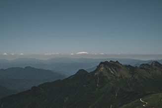 A panoramic view from a mountain peak showing layered ridges fading into the distance