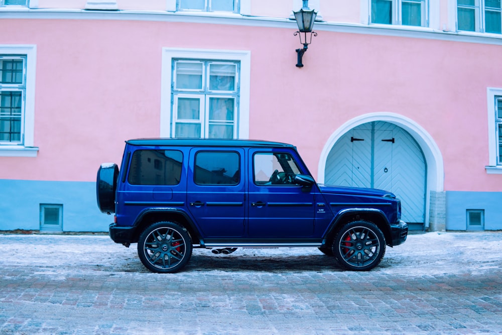 Ein blauer Lastwagen parkt vor einem rosa Gebäude