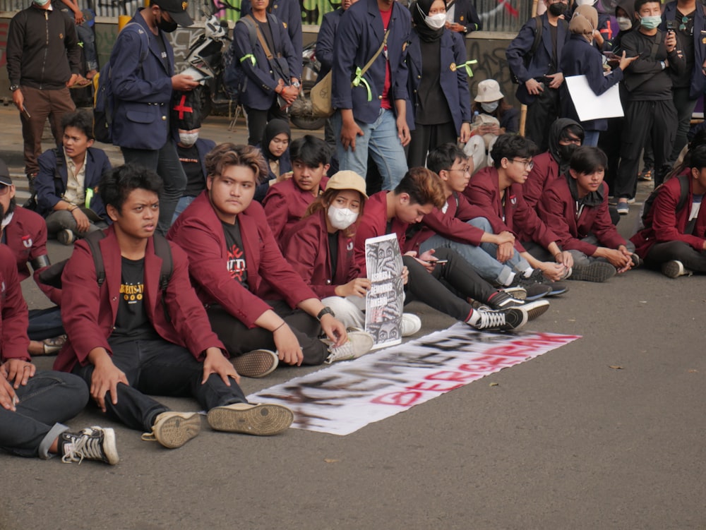 a group of people sitting on the ground holding signs