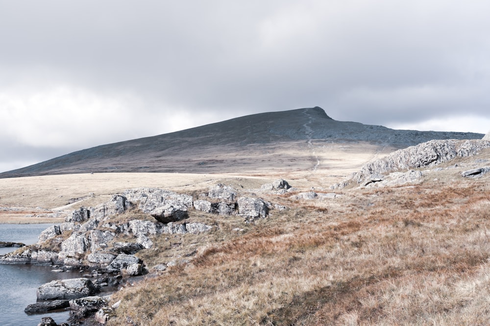 a rocky hillside with a body of water and a hill in the background