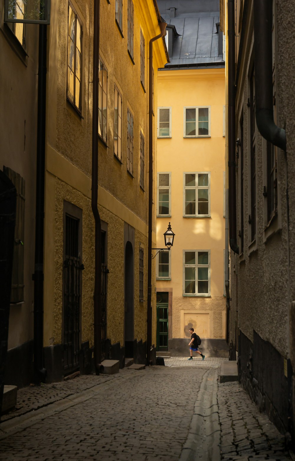a person walking on a cobblestone street between buildings