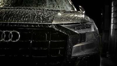 Close-up shot of a luxury car’s gleaming black paint finish under studio lighting with golden reflections
