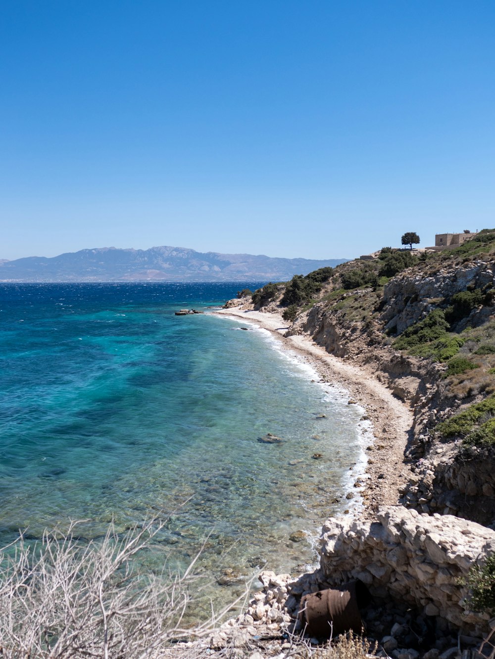 a rocky beach with a body of water in the background