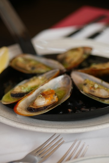 A close-up of a delicious mussel dish topped with a rich sauce.