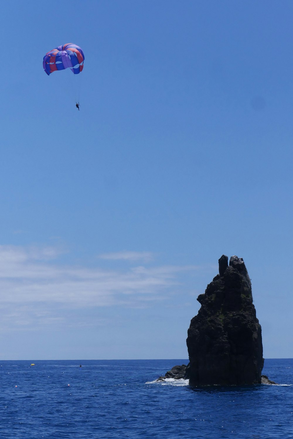 a person parasailing over a rock in the water