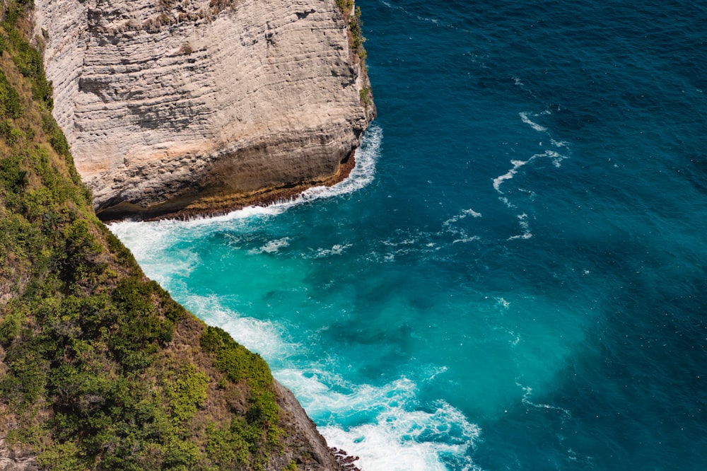 a rocky cliff next to a body of water