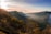A vibrant snapshot of a traveler standing on a cliff overlooking a misty mountain valley at sunrise.