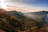 A vibrant snapshot of a traveler standing on a cliff overlooking a misty mountain valley at sunrise.