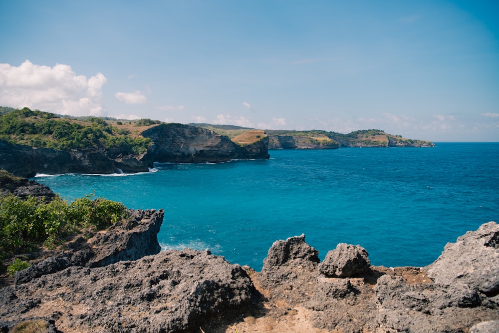 a rocky beach with a body of water in the background