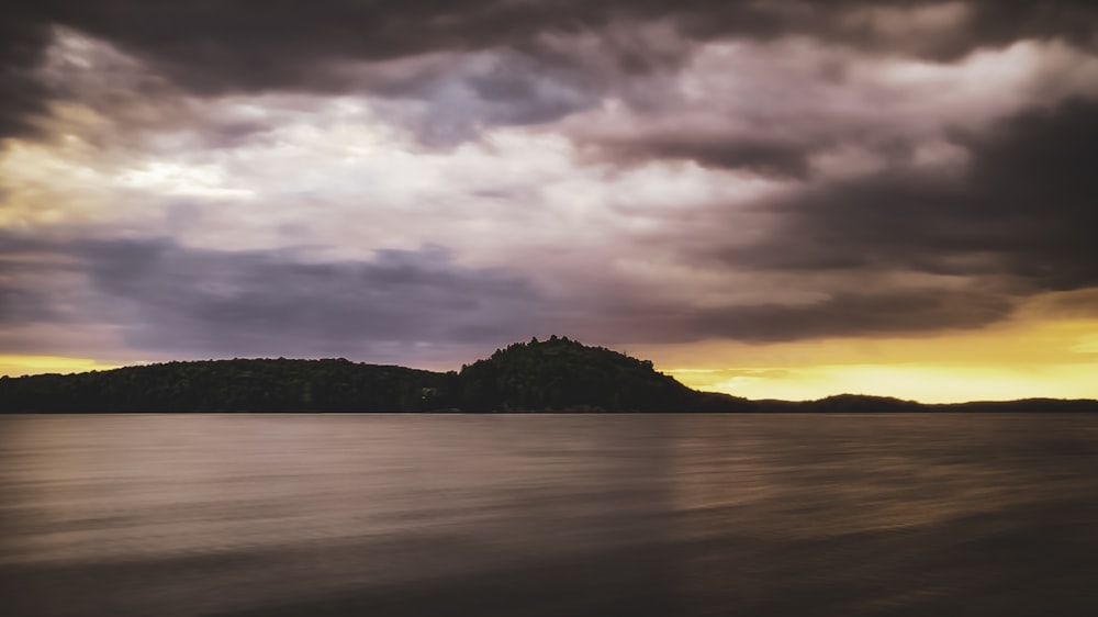 a body of water with a hill in the distance