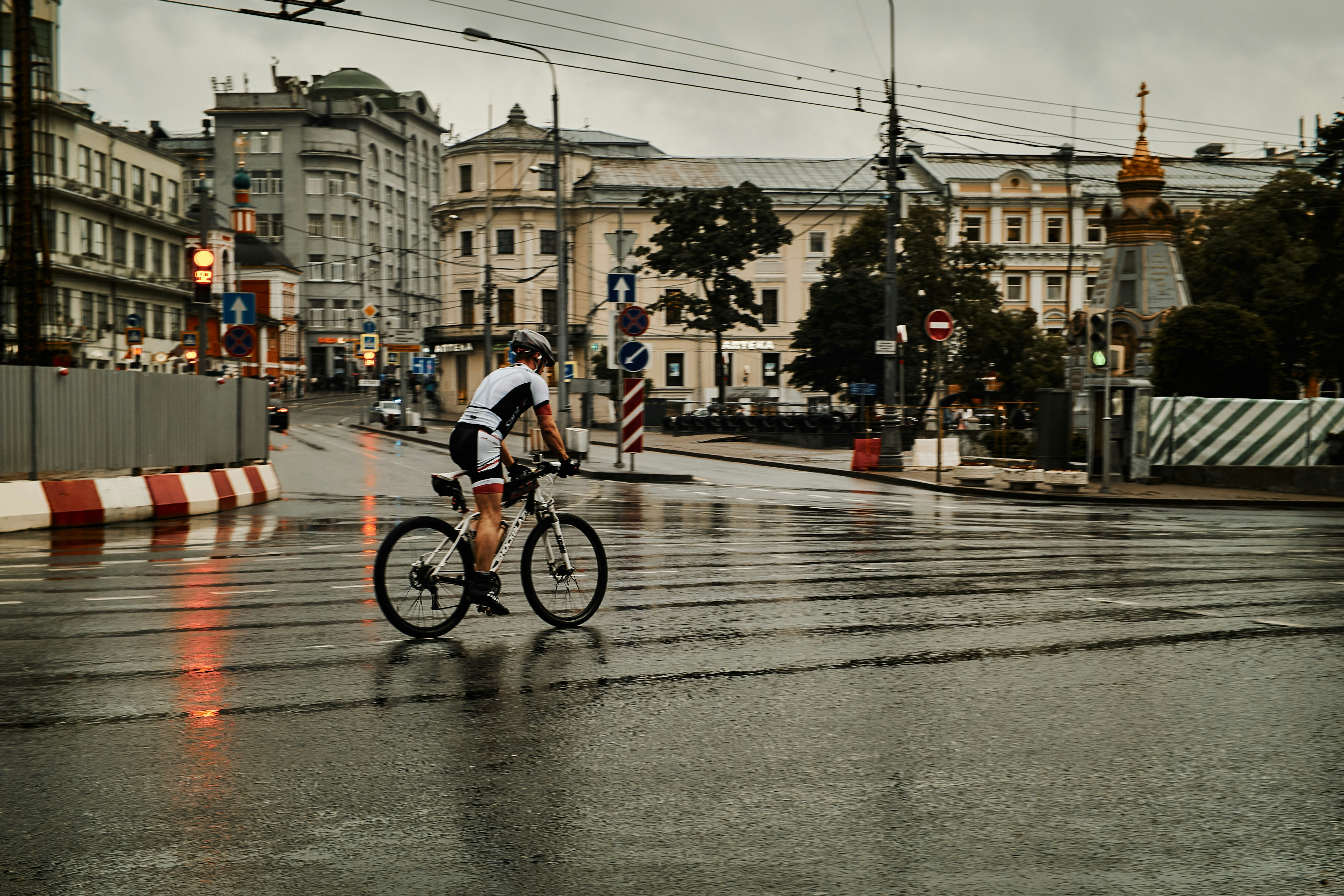 uma pessoa andando de bicicleta em uma rua molhada