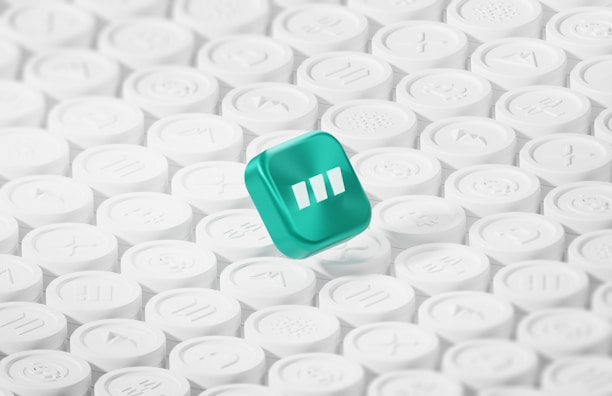 A teal cube with a play button symbol is surrounded by numerous white circular buttons, each featuring different symbols. The teal cube stands out prominently against the uniform white background.