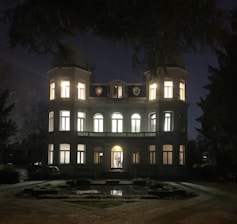 Elegant exterior view of the manor at dusk with warm lights glowing from the windows.