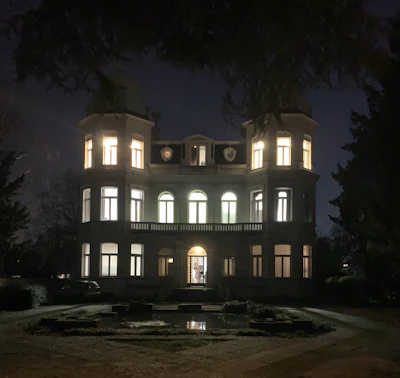 A stunning nighttime view of the estate illuminated with warm outdoor lighting.