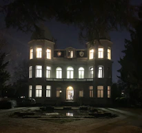 A lavish mansion’s grand entrance illuminated by elegant outdoor lighting.