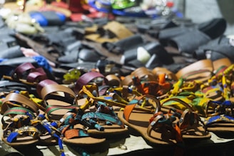 Colorful sandals displayed on a sunny outdoor table with natural elements around.