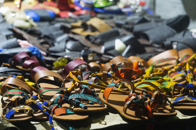 Close-up of colorful crochet sandals with tropical patterns displayed on a wooden table.