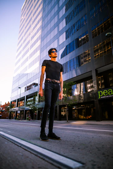 Close-up of a person confidently wearing black frame sunglasses with blue mirrored lenses in an urban setting.
