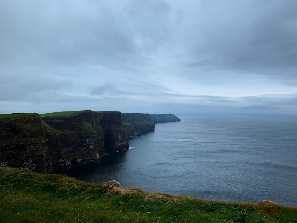 a cliff next to the water with Cliffs of Moher in the background