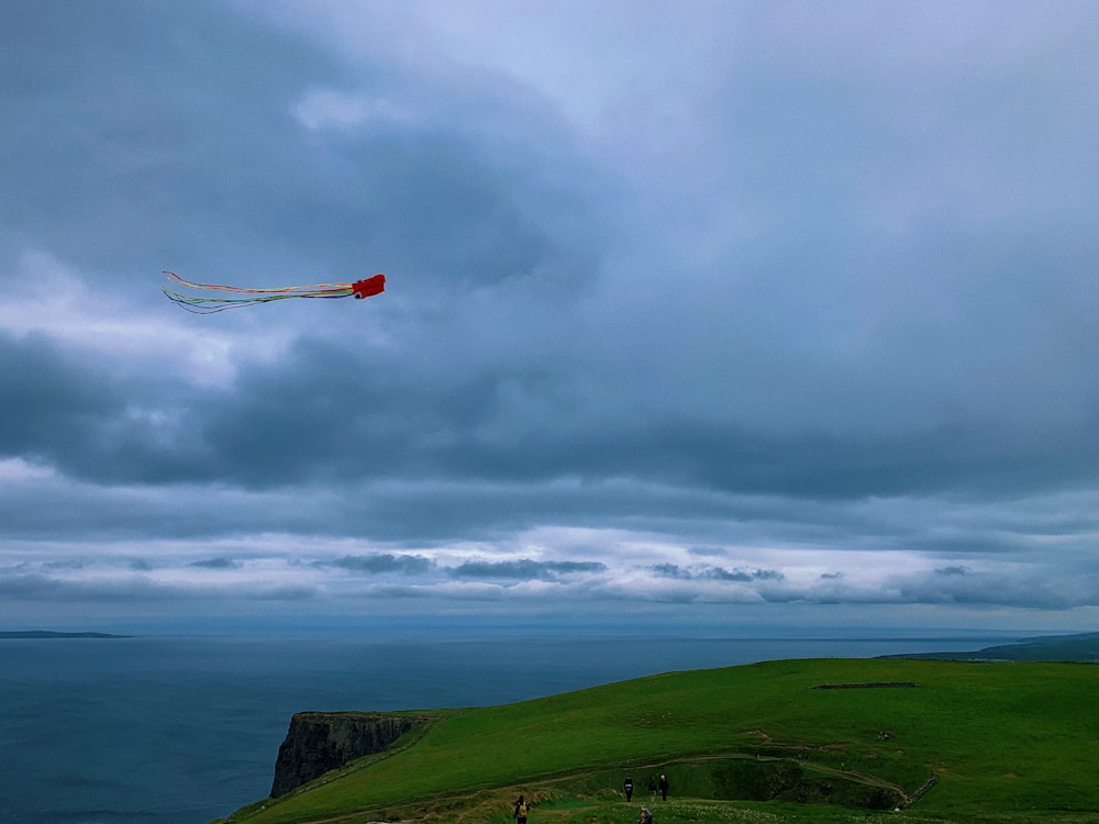 a kite flying over a grassy hill