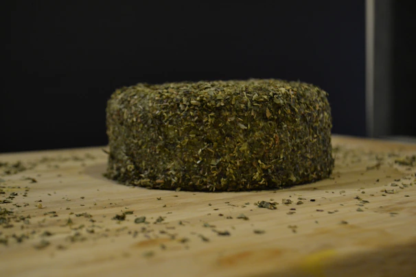 Artisanal donkey milk cheese wheels resting on a wooden board with herbs.