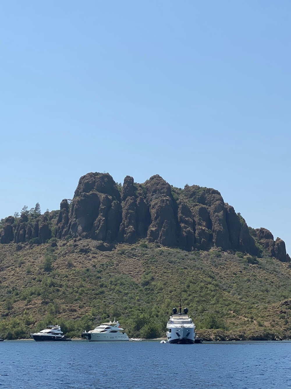 a group of boats in the water by a rocky mountain