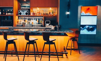 a bar with stools and a counter with a screen on it