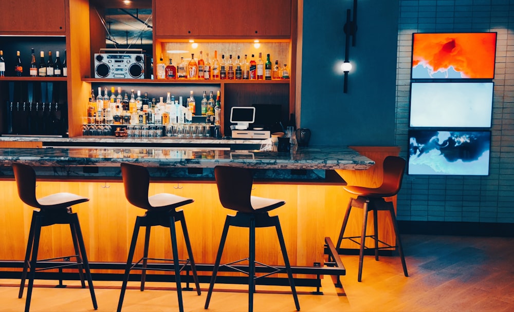 a bar with stools and a counter with a screen on it