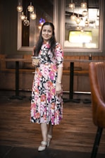 A stylish woman in elegant attire, smiling and enjoying a drink at a bar.