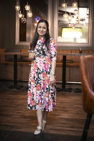 Model showcasing a pastel-toned cocktail dress in a bright, airy room.
