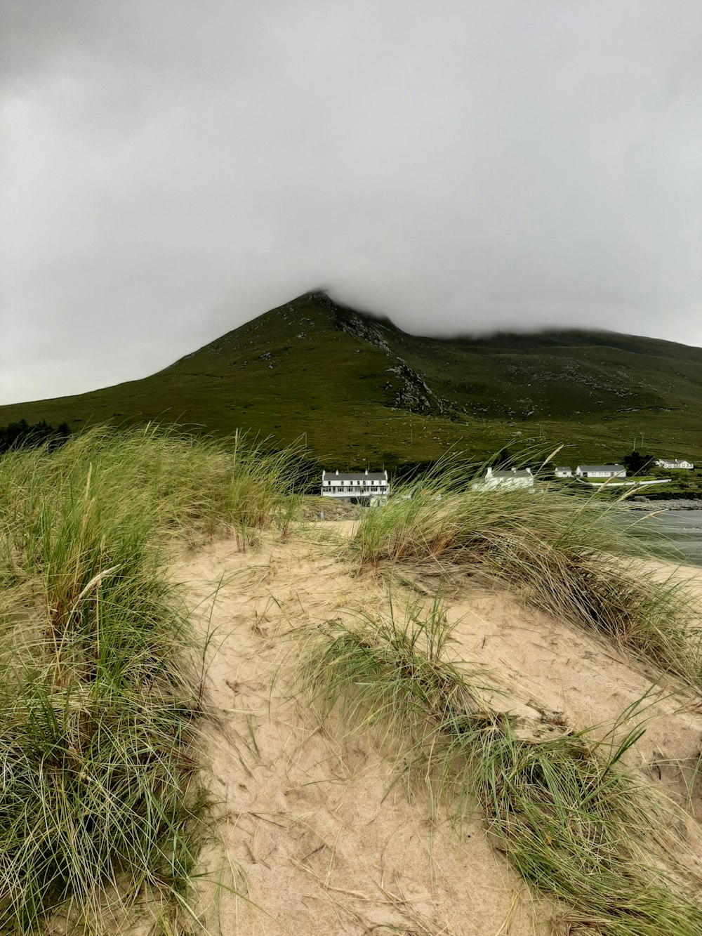 uma praia de areia com uma colina no fundo