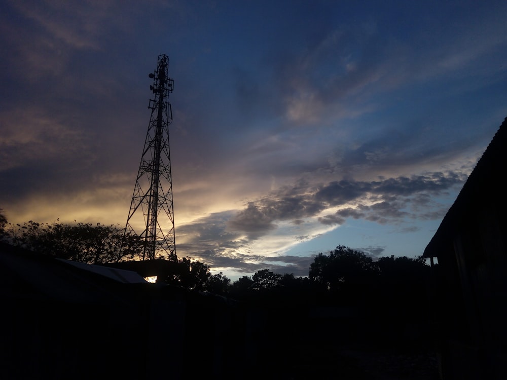 a tower with a wire fence and trees in the background