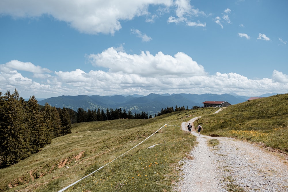 a dirt road with people on it and a house in the distance