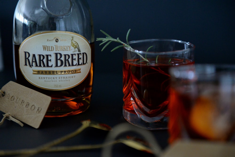 a bottle of alcohol next to a glass of red liquid