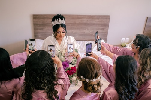 a person in a crown holding a cell phone in front of a group of people