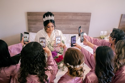 a person in a crown holding a cell phone in front of a group of people