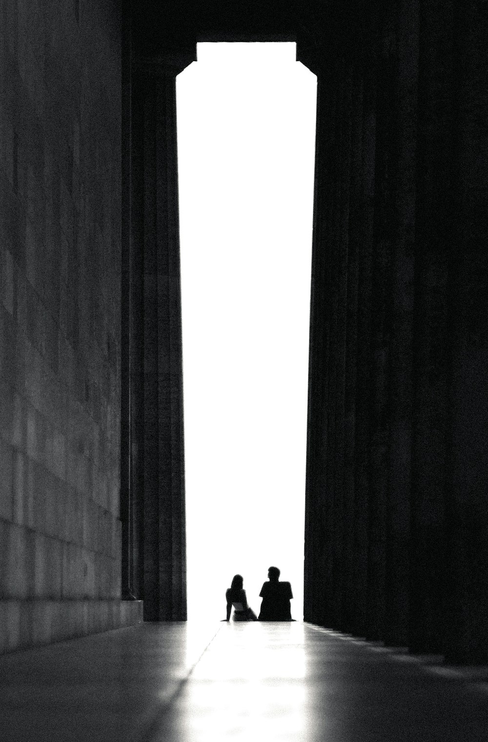 a couple of people sitting in a hallway looking out at a large window