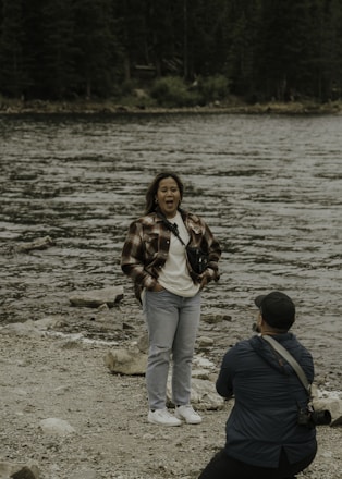 a woman holding a camera and a man standing on a beach