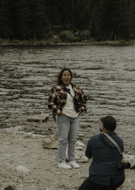 a woman holding a camera and a man standing on a beach